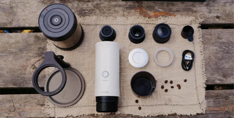 Coffee travel products and gear laid out on table including portable espresso maker and travel mug